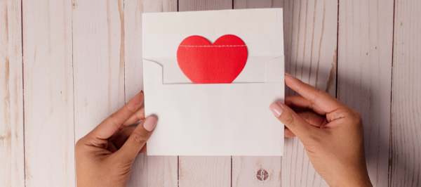 hands open a whit envelope with a red heart inside